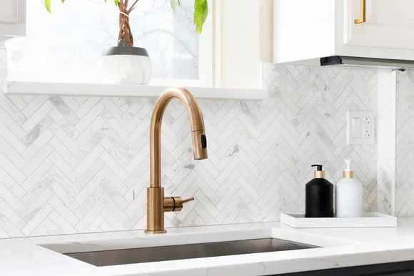 Moderne Küchenspüle mit goldfarbenem Wasserhahn